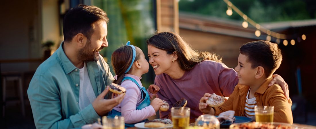 Happy family having fun while eating at dining table on a patio in spring day.