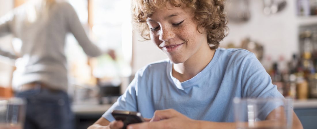 Teenage boy using smartphone at dining table