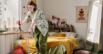 Teenage girl turning on the smartphone standing on tripod for online streaming in her bedroom